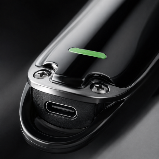 Macro close-up of a rechargeable hair trimmer USB charging port with premium black finish, metal screws, and charging indicator detail showcasing convenient USB charging capability.