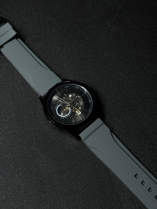 Grey strap replica watch with skeleton dial, automatic-style movement display, black case and premium silicone band on dark background