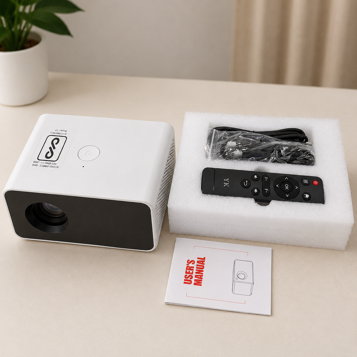 Portable LED video projector with remote control, power cable, and user manual displayed on a clean tabletop. Compact white HD projector with accessories included for home entertainment and presentations.