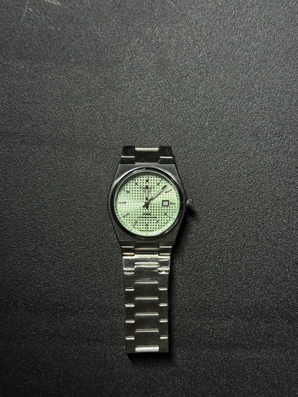 Replica watch with textured light green waffle dial, stainless steel integrated strap, date display and modern luxury sports watch styling