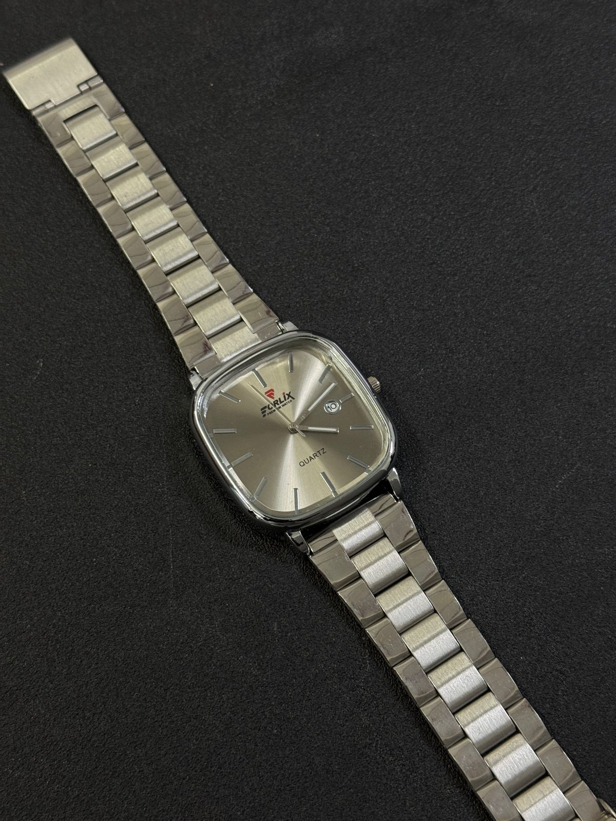 Silver wristwatch with a metallic band on a black background