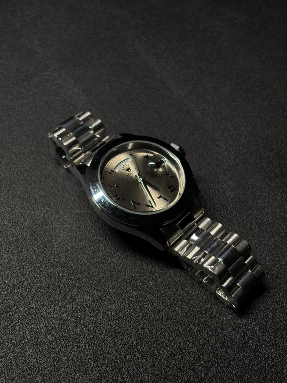 Replica silver dial day date watch with polished stainless steel case, Arabic numeral hour markers and premium metal bracelet close-up
