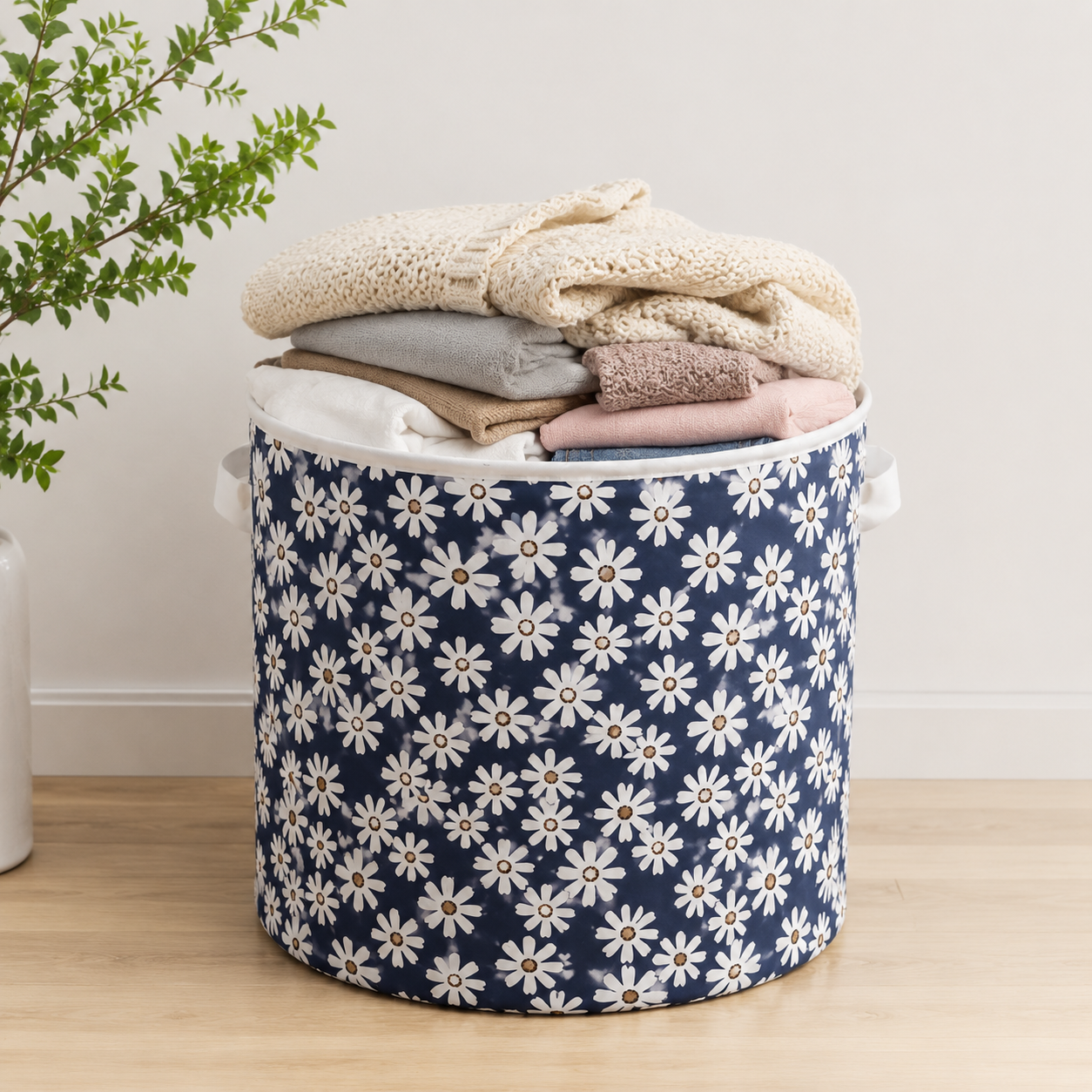 Round floral fabric laundry basket filled with folded clothes, featuring a stylish blue daisy pattern for home storage and organisation.