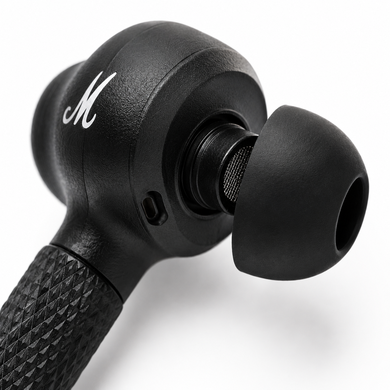 Close-up macro view of a premium black wireless earbud featuring a soft silicone ear tip, precision speaker mesh, textured stem grip, built-in microphone, and ergonomic in-ear design
