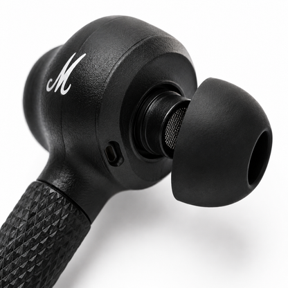 Close-up macro view of a premium black wireless earbud featuring a soft silicone ear tip, precision speaker mesh, textured stem grip, built-in microphone, and ergonomic in-ear design
