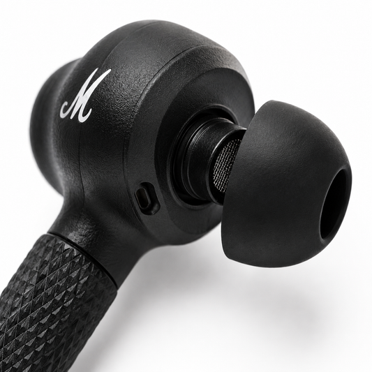 Close-up macro view of a premium black wireless earbud featuring a soft silicone ear tip, precision speaker mesh, textured stem grip, built-in microphone, and ergonomic in-ear design