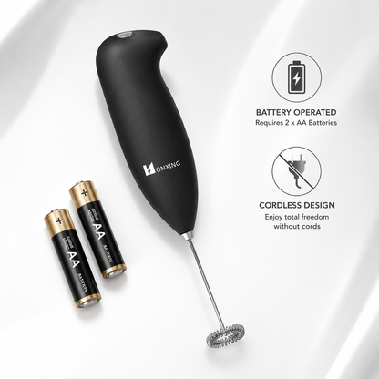 Battery-operated handheld milk frother with ergonomic soft-touch black handle and stainless steel whisk displayed beside two AA batteries, highlighting cordless operation and portable coffee frothing convenience.