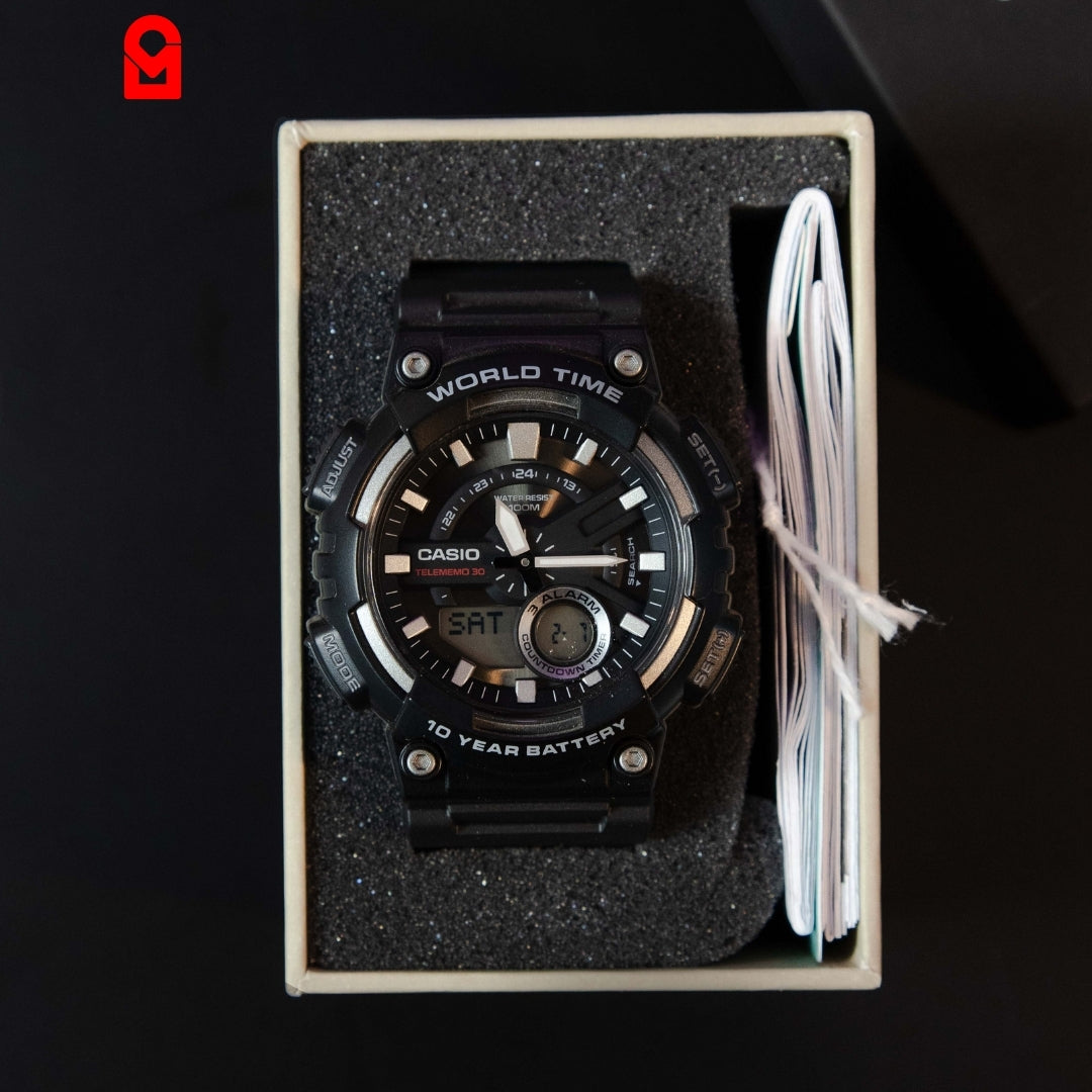 Black analog digital sports watch with world time display placed inside packaging box.