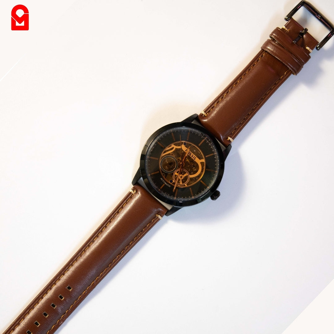 Black skeleton automatic watch with brown leather strap displayed on white background.
