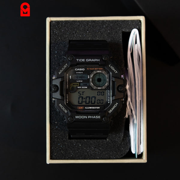 Black digital sports watch with tide graph and moon phase display placed inside packaging box.