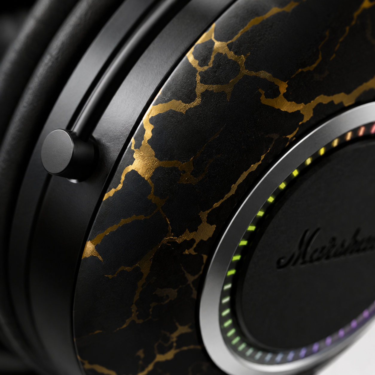 Extreme close-up of the premium headphone ear cup featuring an elegant black and gold marble finish, RGB LED light ring, durable metal support arm, and high-quality textured construction with luxury studio lighting.