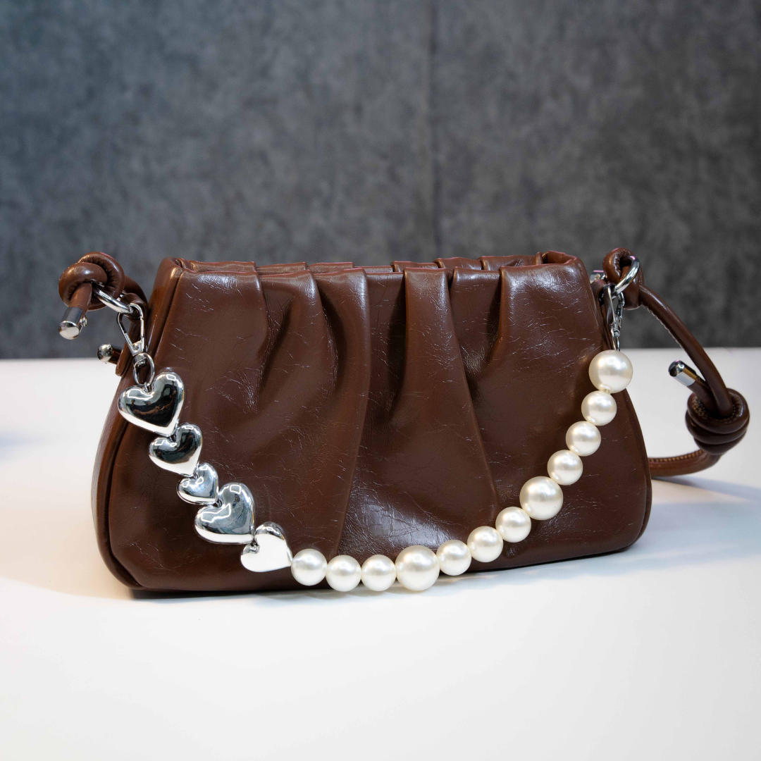 Brown ruched shoulder bag with pearl chain and heart charm detail.