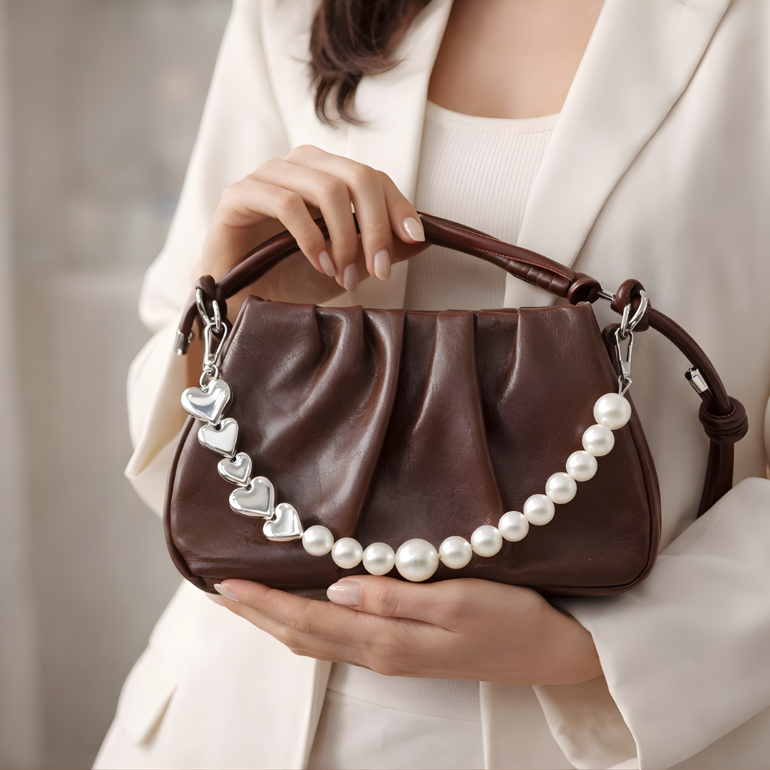 Brown ruched shoulder bag with pearl chain detail worn with neutral outfit.