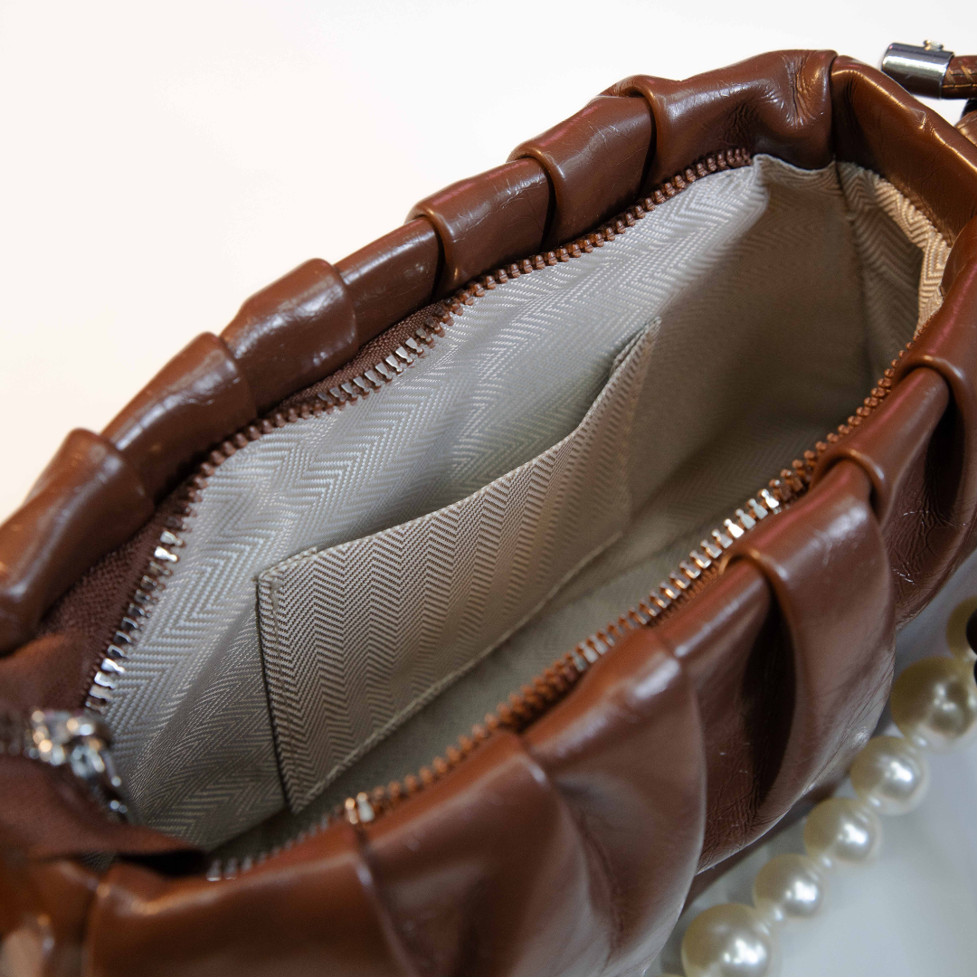 Brown ruched shoulder bag interior with zip closure and fabric lining.