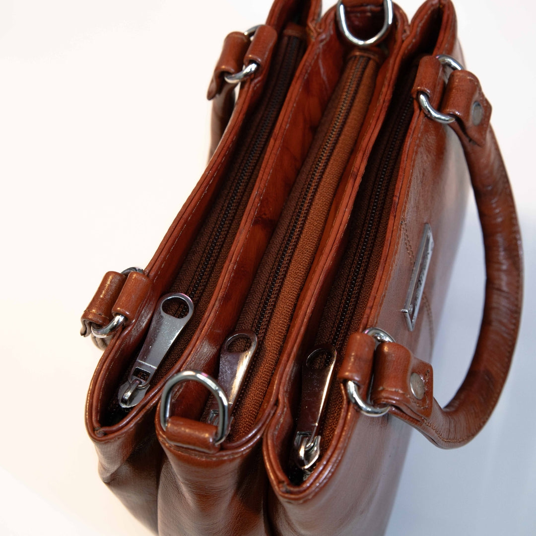 Brown leather tote bag showing multiple zip compartments for organised storage.