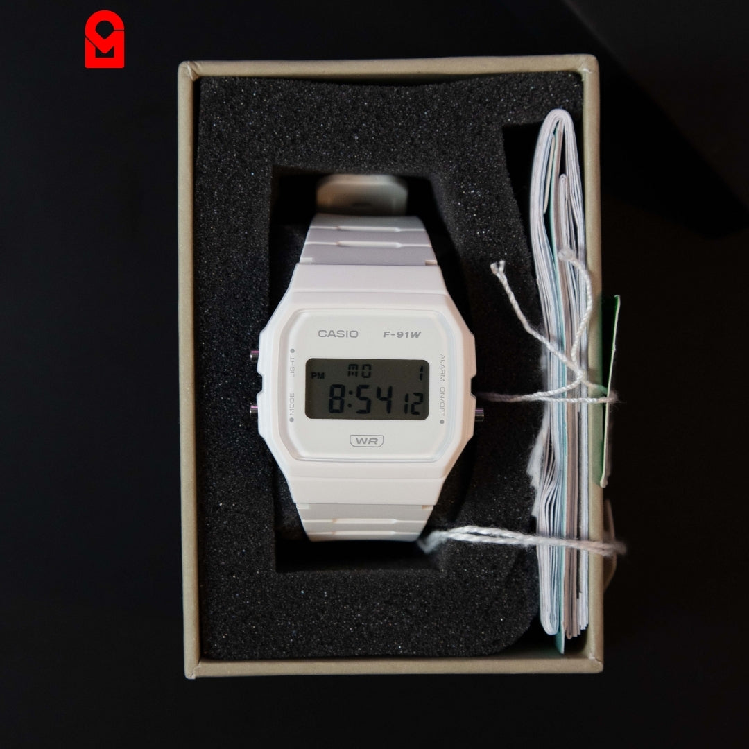 Digital rectangular watch with white resin strap displayed inside watch box.