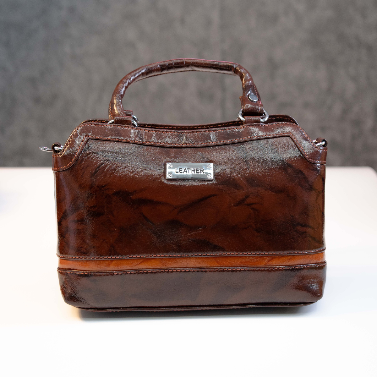 Classic genuine leather top handle bag in brown with structured design.