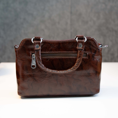 Brown leather top handle bag showing back zip pocket and smooth finish.