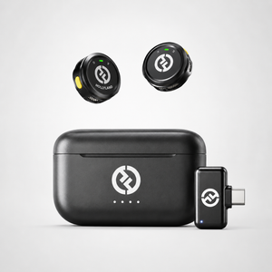 Compact wireless lavalier microphone system featuring two button-sized transmitters, USB-C receiver adapter, and portable charging case displayed on a clean white background.