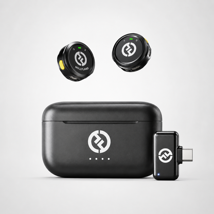 Compact wireless lavalier microphone system featuring two button-sized transmitters, USB-C receiver adapter, and portable charging case displayed on a clean white background.