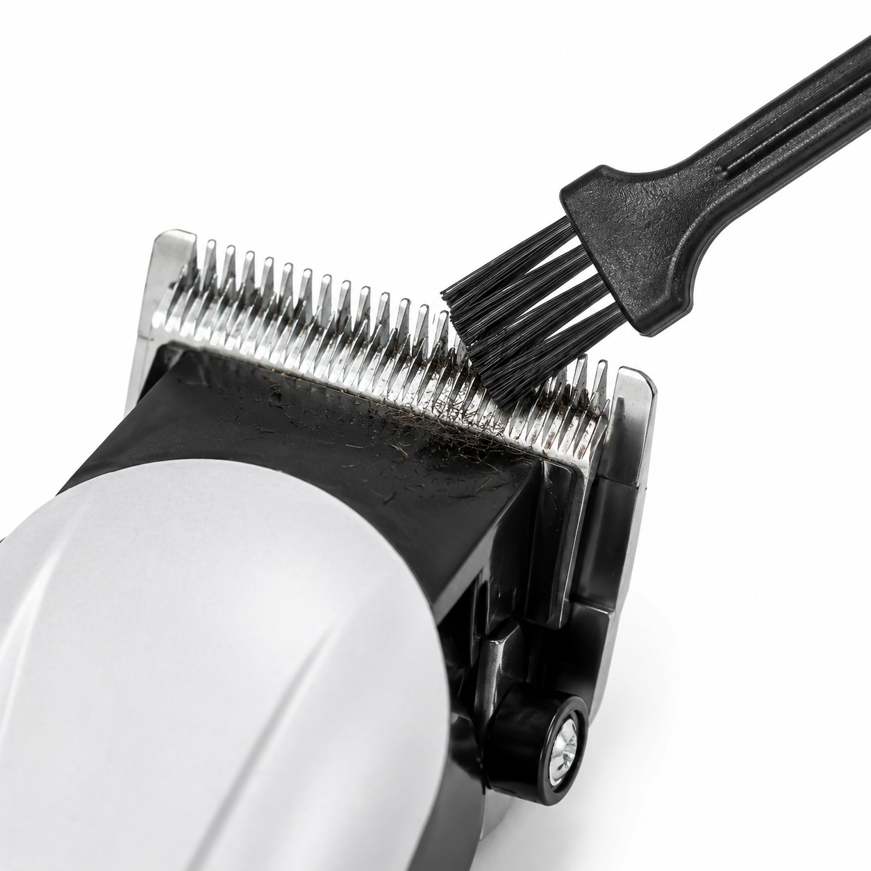 Close-up of a stainless steel hair clipper blade being cleaned with the included cleaning brush, highlighting precision cutting teeth and easy maintenance.