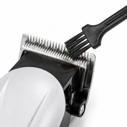 Close-up of a stainless steel hair clipper blade being cleaned with the included cleaning brush, highlighting precision cutting teeth and easy maintenance.