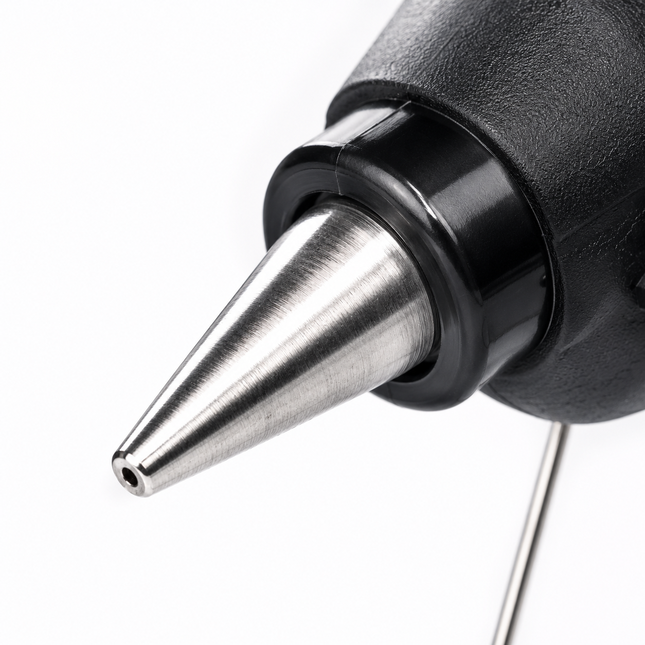 Macro shot of the precision metal nozzle on a 100W hot melt glue gun, ideal for accurate adhesive application in crafts, DIY and home repairs.