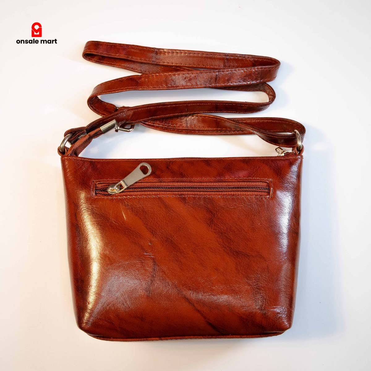 Brown leather crossbody bag showing back zip pocket and smooth leather finish.