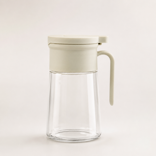 Glass Oil Dispenser Bottle with Handle isolated on white background, clear glass oil container with flip-top lid for kitchen oil and vinegar storage.