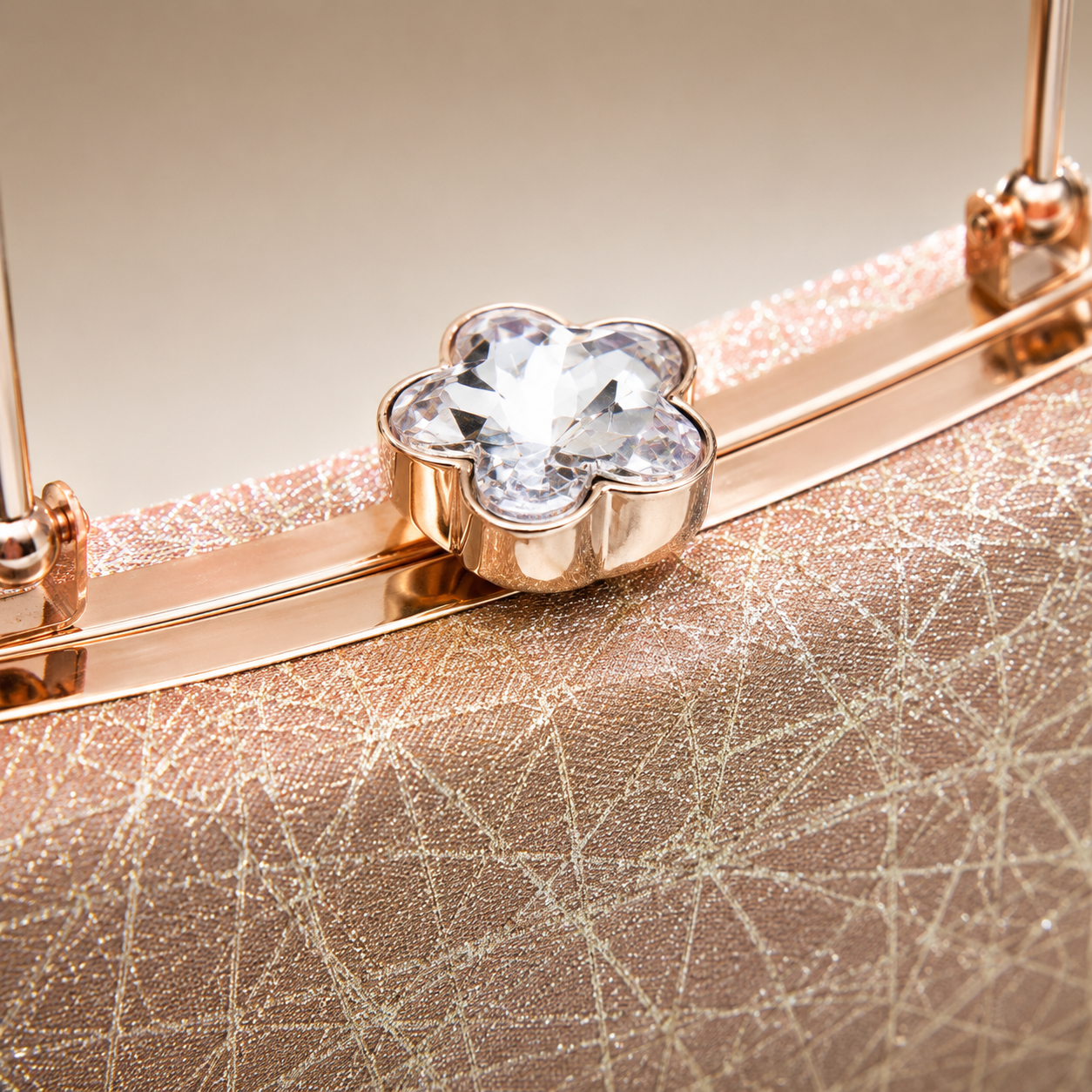 Close-up of crystal flower clasp on a rose gold glitter clutch bag, highlighting premium metallic frame and sparkling textured fabric.