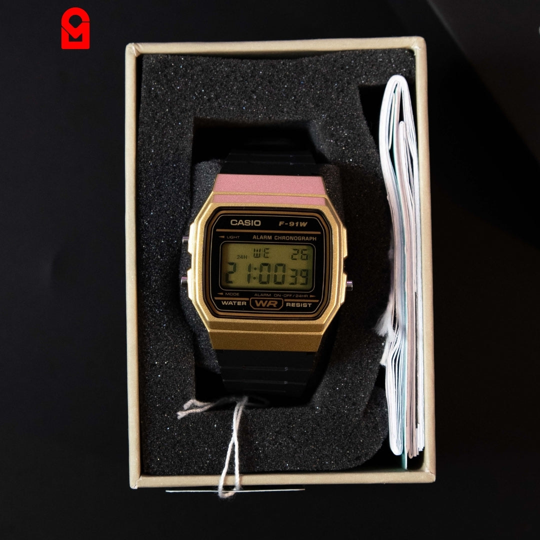 Digital rectangular wrist watch with LCD display and gold tone case in packaging.
