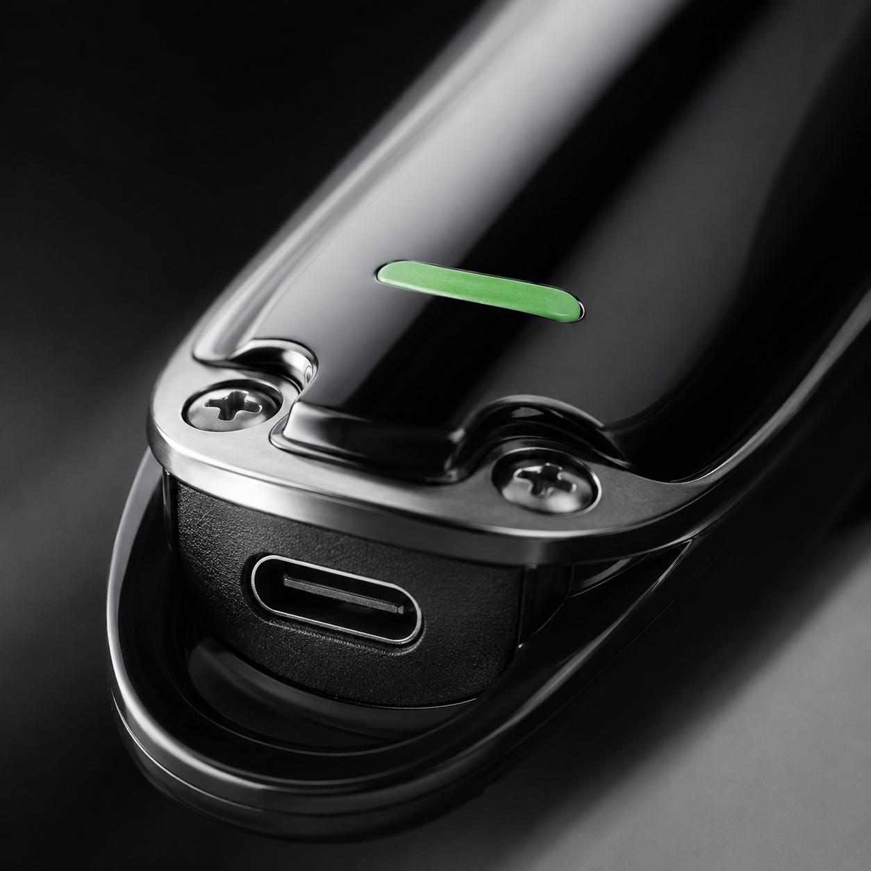 Macro close-up of a rechargeable hair trimmer USB charging port with premium black finish, metal screws, and charging indicator detail showcasing convenient USB charging capability.