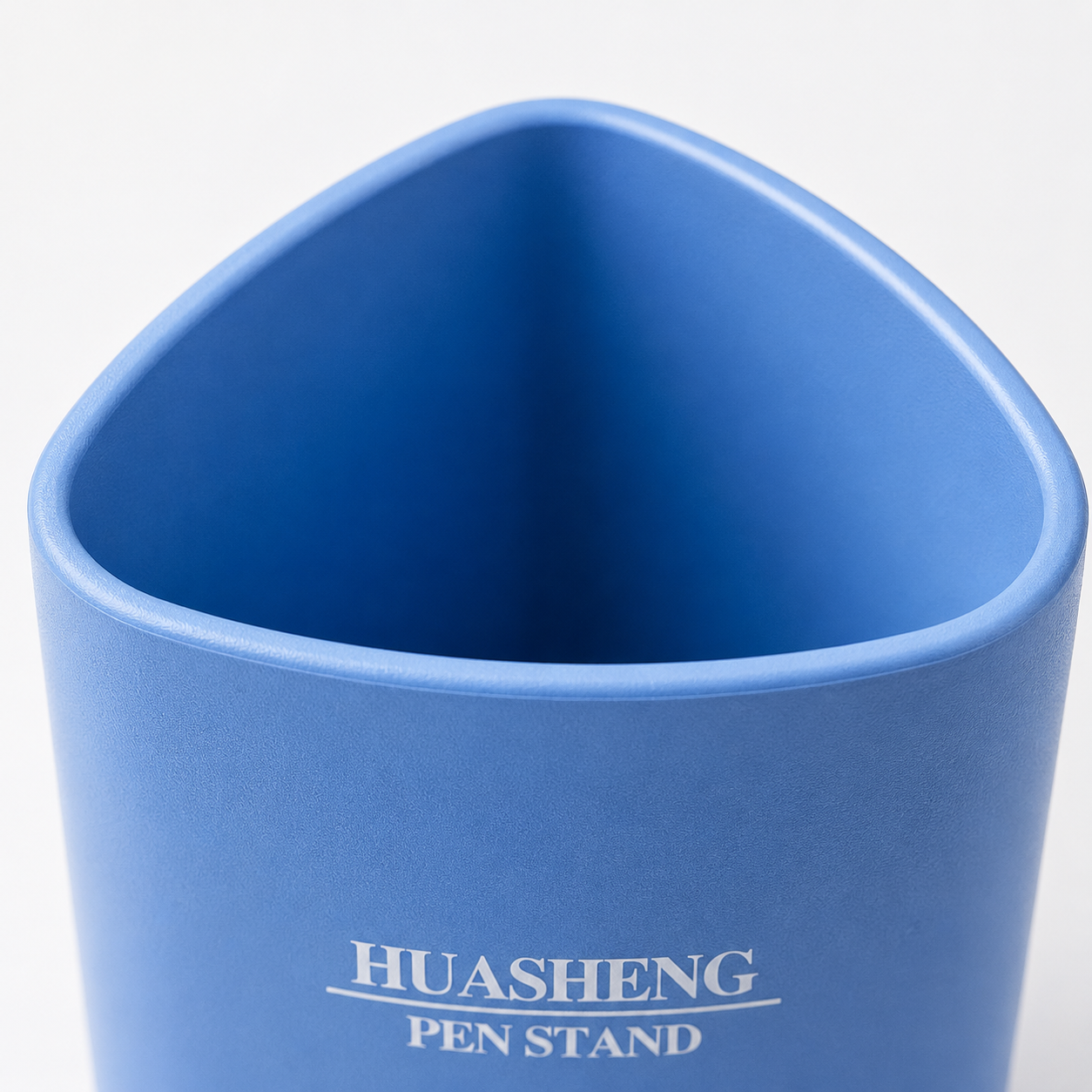 Close-up view of the blue Huasheng Pen Stand featuring a rounded triangular opening, smooth matte plastic finish, and modern minimalist design