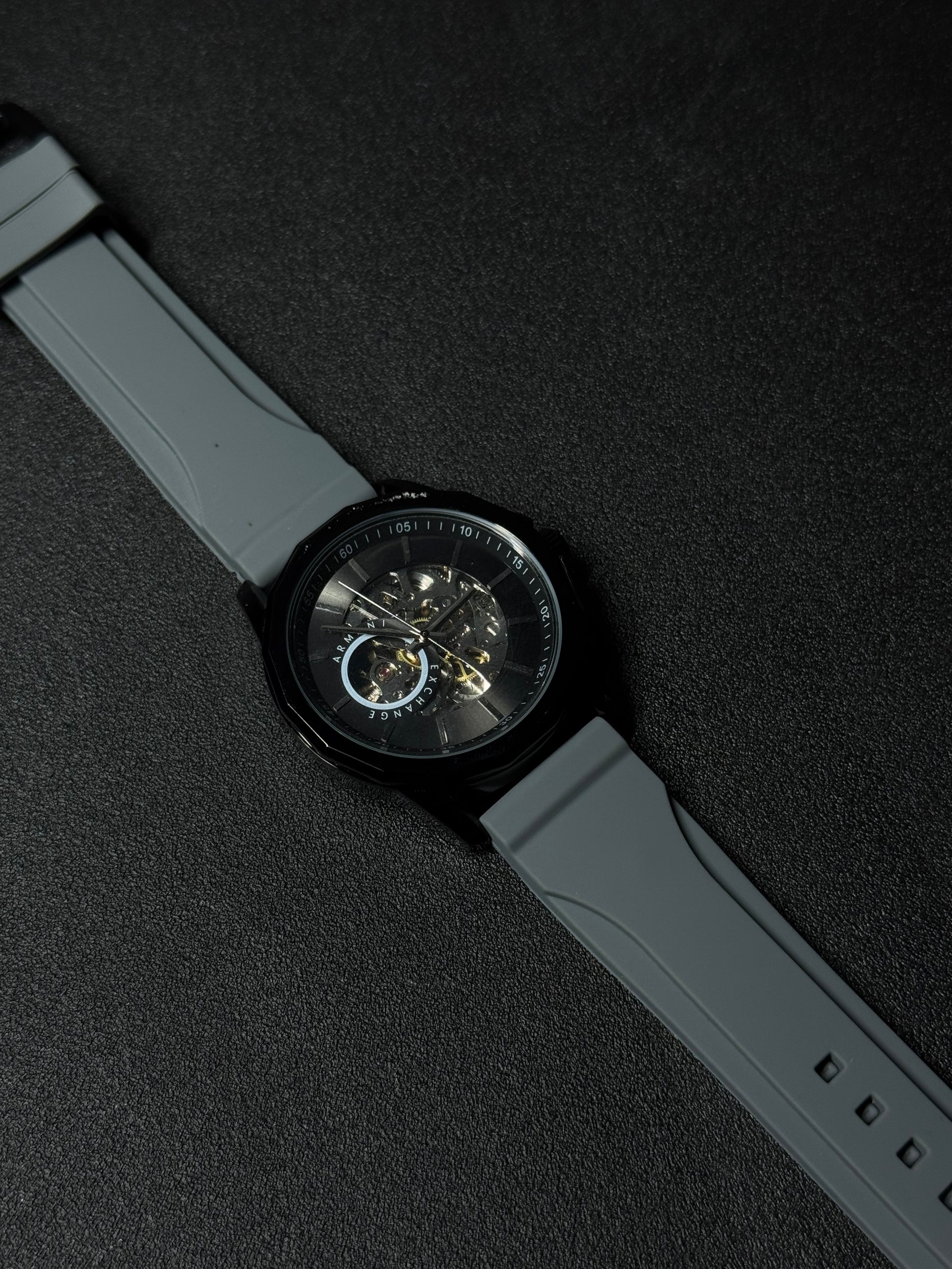 Grey strap replica watch with skeleton dial, automatic-style movement display, black case and premium silicone band on dark background