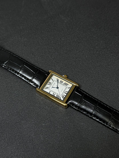 Vintage watch with black leather strap and gold case on a dark gray background