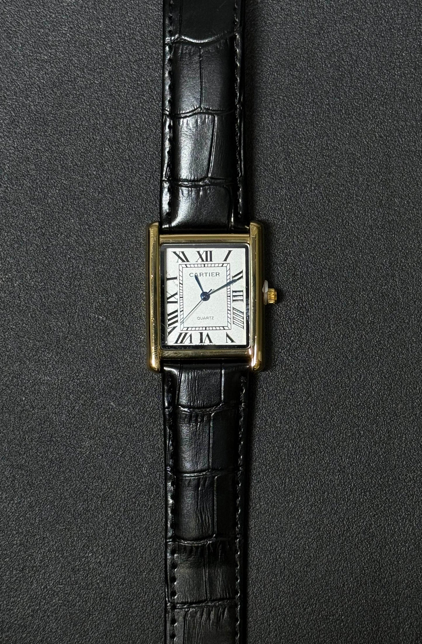 Luxury inspired replica watch with black crocodile texture leather strap, white rectangular dial and Roman numeral hour markers 