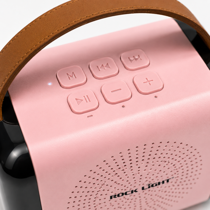 Close-up of the portable karaoke speaker showing top-mounted media controls, volume buttons, mode button, LED indicator, and premium carry handle with soft pink finish.