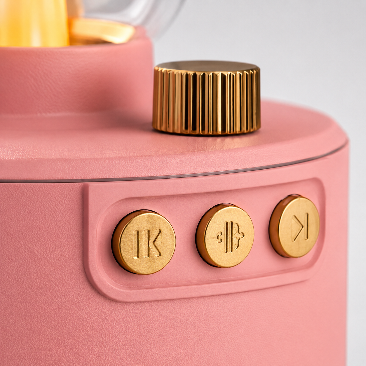 Macro close-up of the vintage Bluetooth speaker featuring gold-finish control buttons and rotary volume knob on a premium textured pink housing.