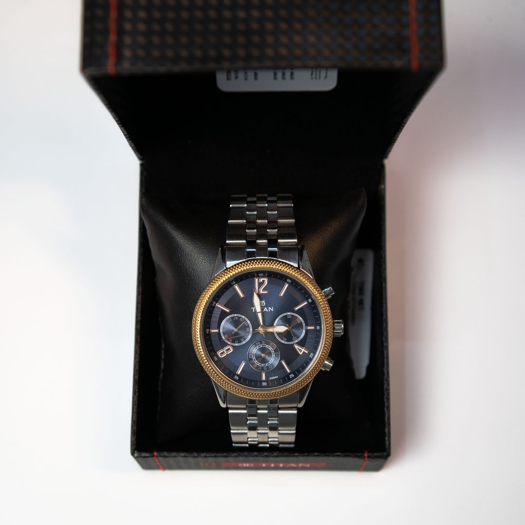 Men’s chronograph watch with black dial and gold tone bezel displayed inside watch box.