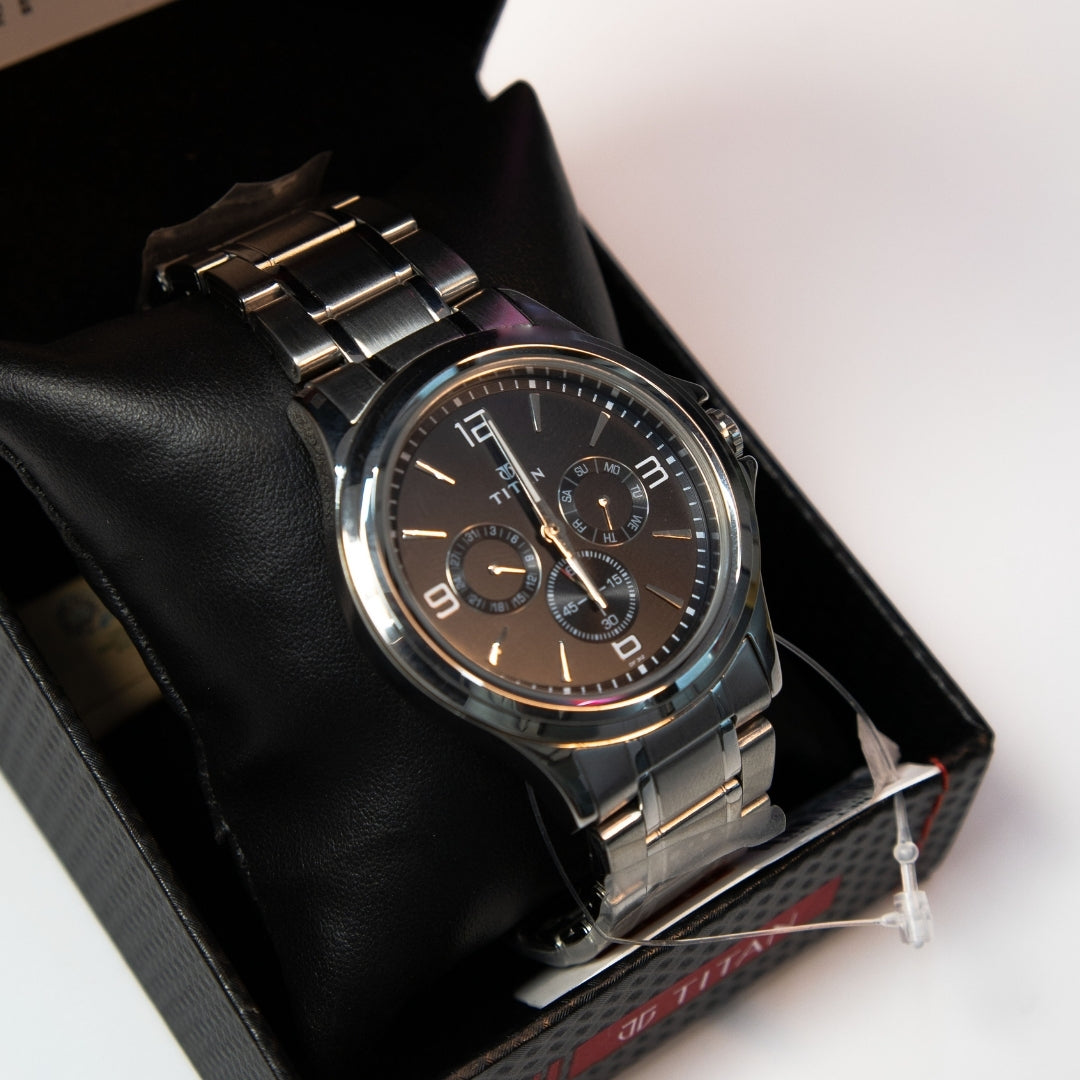 Close-up of men’s analog multi function watch with black dial and steel strap.