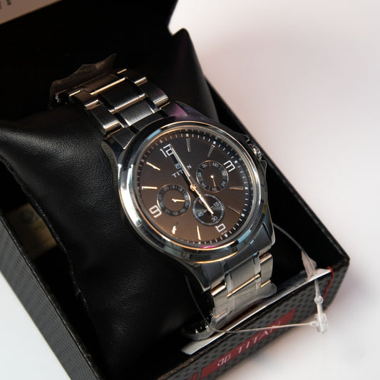 Close-up of men’s analog multi function watch with black dial and steel strap.
