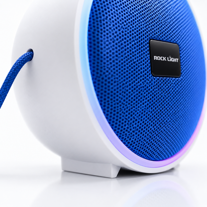 Close-up of a portable RGB Bluetooth speaker featuring a blue metal mesh grille, colourful LED light ring, durable white housing and integrated carry strap.