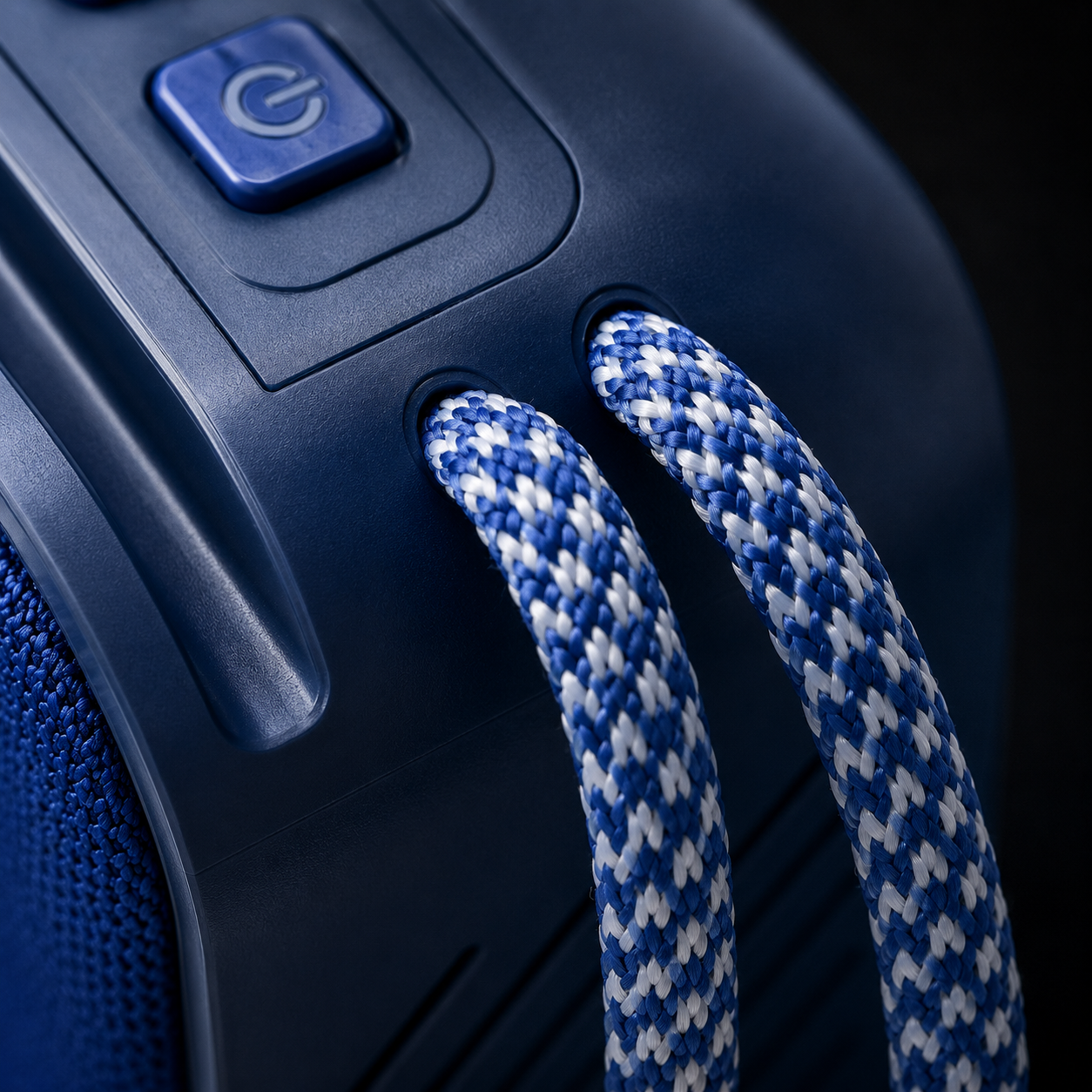 Macro close-up of the braided blue and white carry strap attached to a portable Bluetooth speaker, showcasing durable construction, premium materials, and textured matte finish.