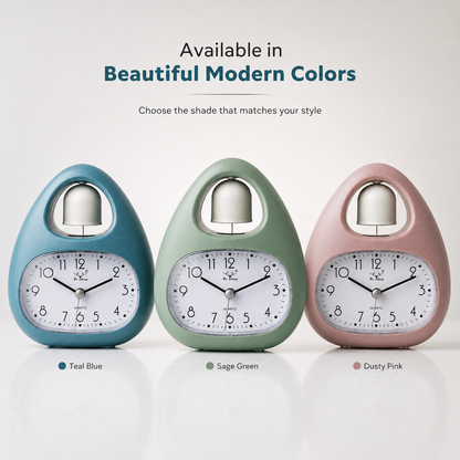 Single bell analog alarm clock available in teal blue, sage green, and dusty pink colors with quartz movement and modern tabletop design.