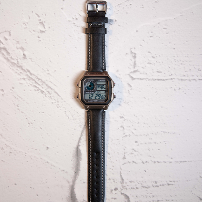 Modern Black Digital Square Watch with leather strap and retro digital display on marble background