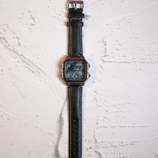 Modern Black Digital Square Watch with leather strap and retro digital display on marble background
