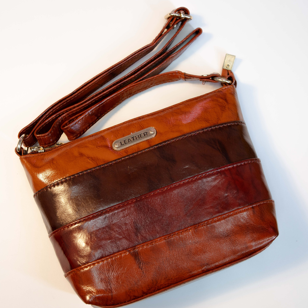 Vintage multi-tone brown leather crossbody bag with adjustable strap.
