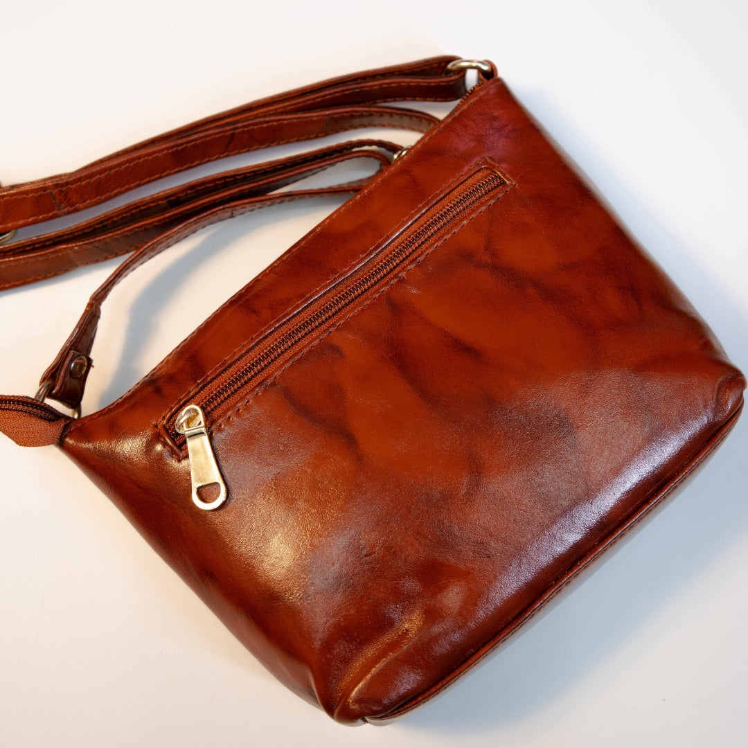 Brown leather crossbody bag showing back zip pocket and smooth leather finish.