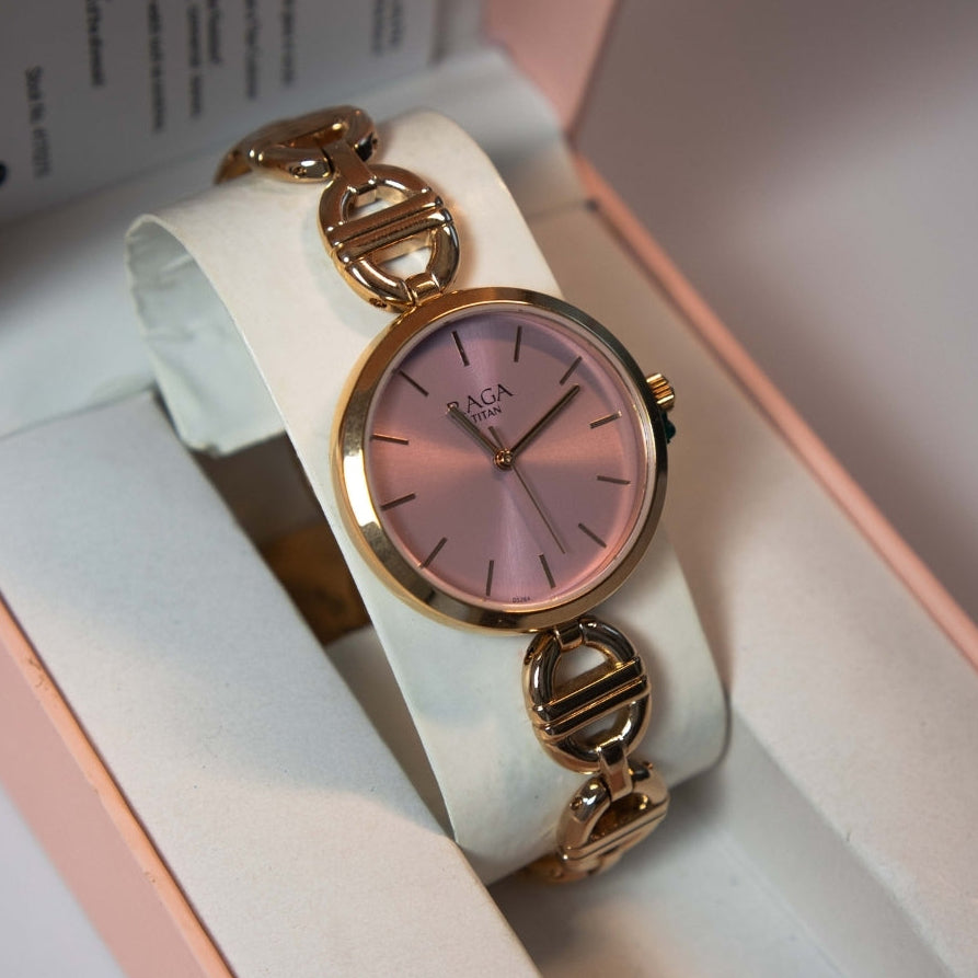Women’s pink dial bracelet watch with gold tone case displayed inside watch box.