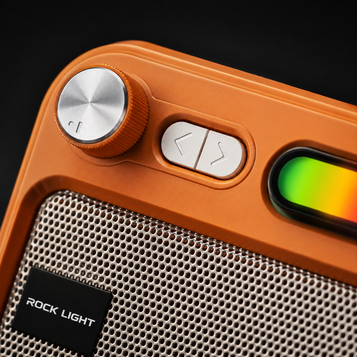 Close-up of a portable wireless speaker showing premium rotary volume knob, navigation buttons, RGB light panel, metallic speaker grille, and retro-inspired design in an orange finish.